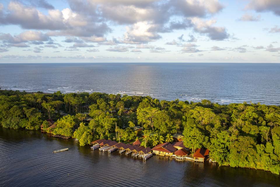 transfer-exclusive-laguna-lodge-aerial Vista aérea del Laguna Lodge en Tortuguero, Costa Rica, mostrando sus muelles privados frente al canal principal y la exuberante selva tropical entre el río y el mar