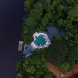 Vista aérea de Pachira Lodge en Tortuguero, destacando su piscina en forma de tortuga y su muelle privado rodeado de selva tropical.
