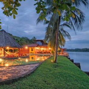 Atardecer en Tortuga Lodge & Gardens, Tortuguero: vista de la piscina iluminada, el rancho con hamacas y el muelle privado frente al canal principal.